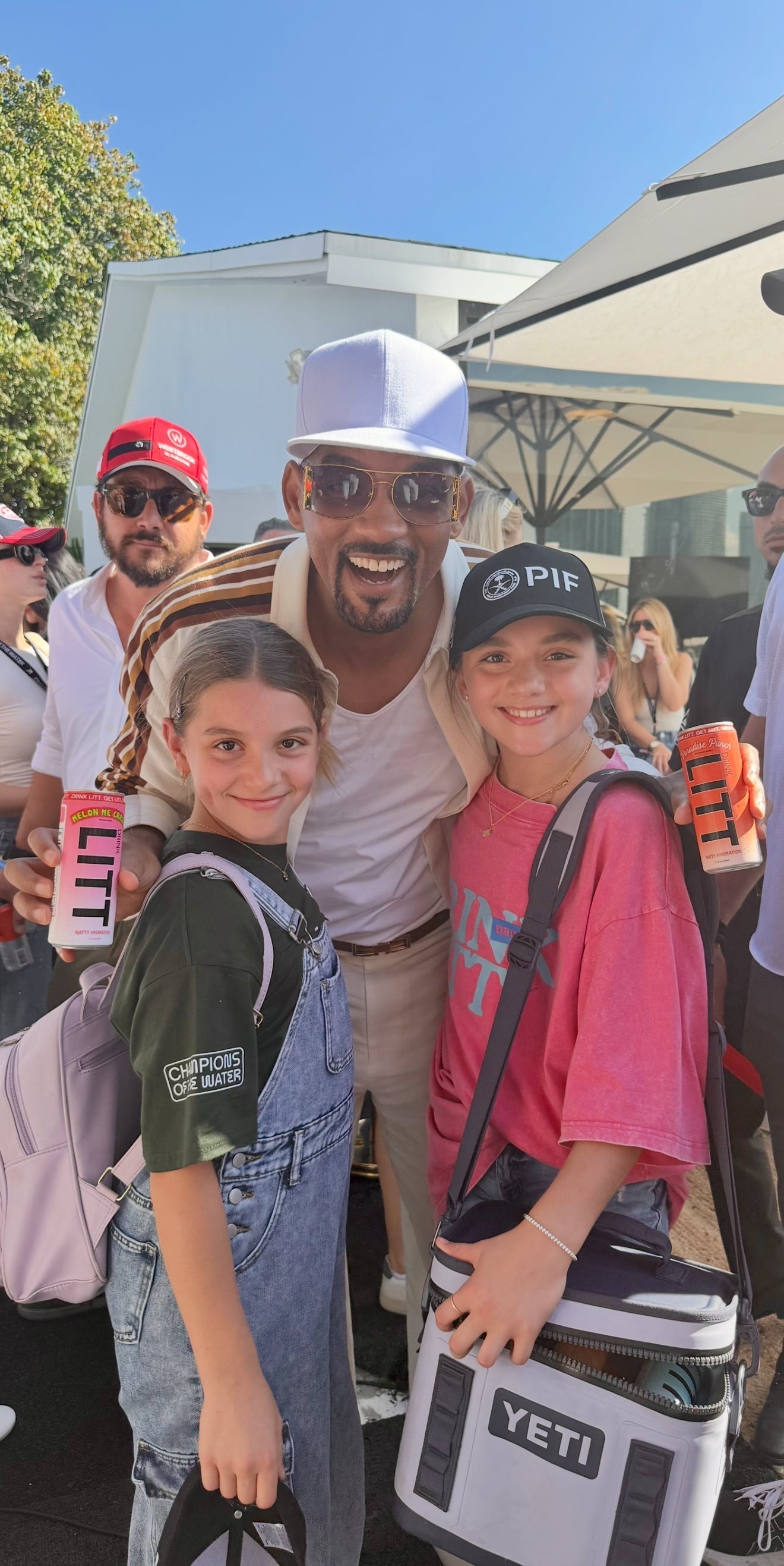 Hollywood celebrity resembling Will Smith holding Drink Litt energy drink with fans at an outdoor event